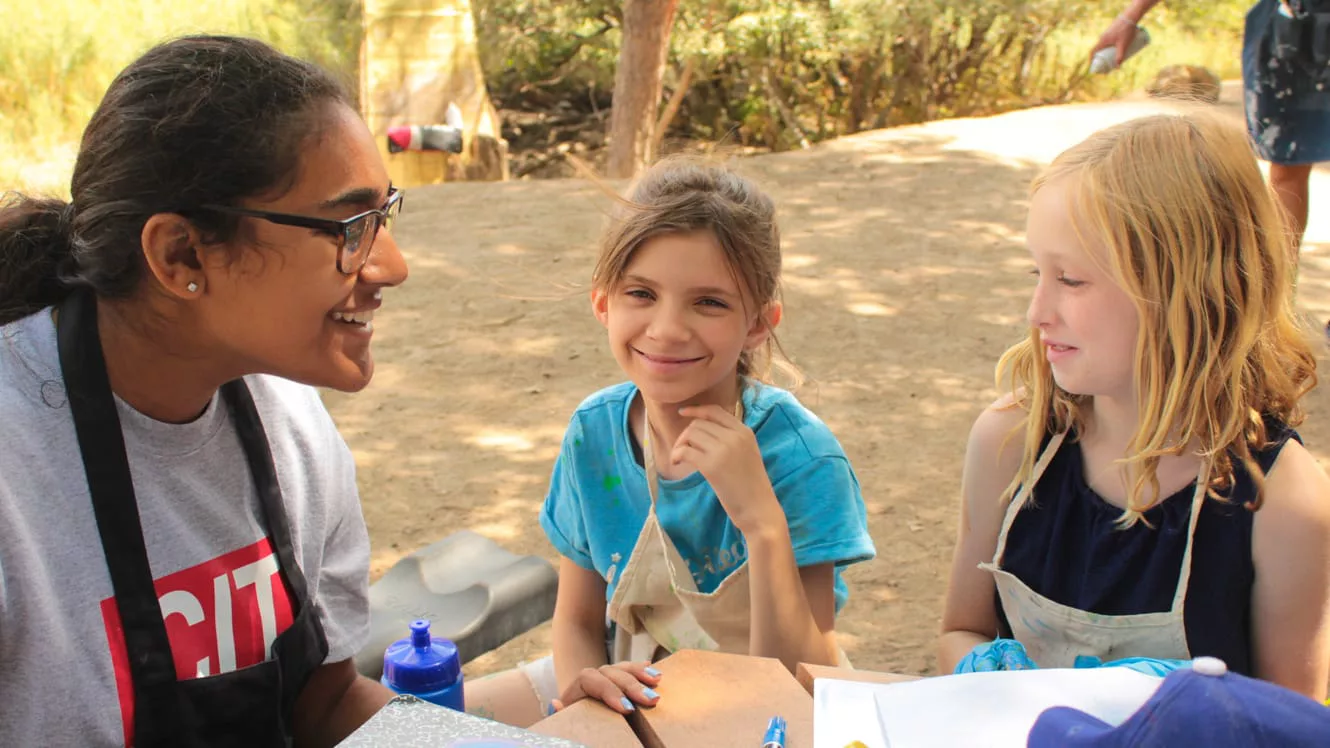 Staff talking to campers during painting activity