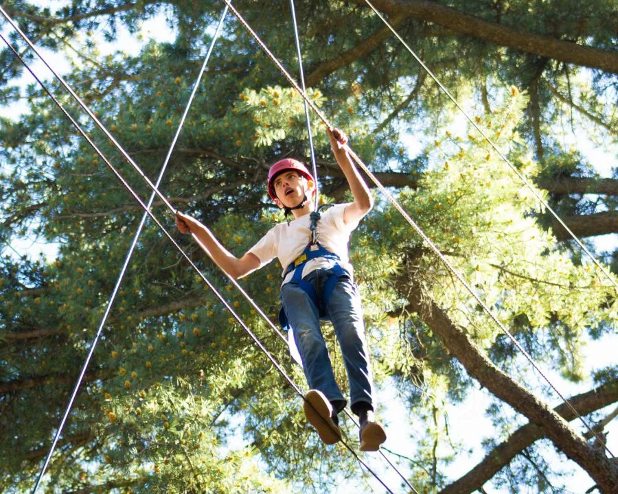 Boy walking on high ropes course wires