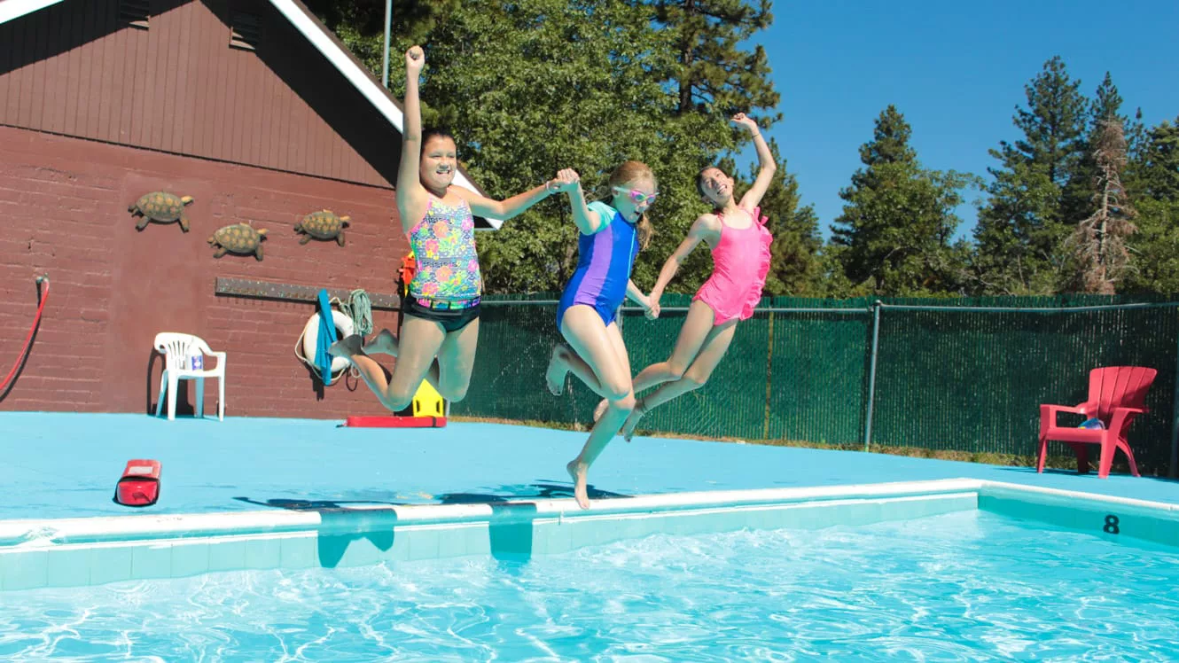 Three girls jumping into swimming pool