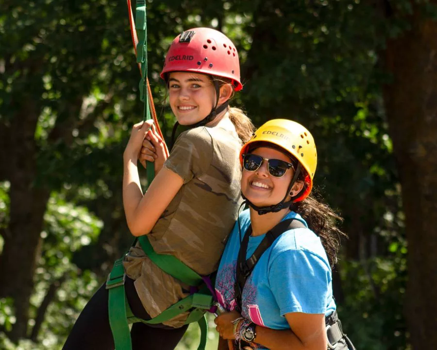 Camper and staff in climbing harnesses