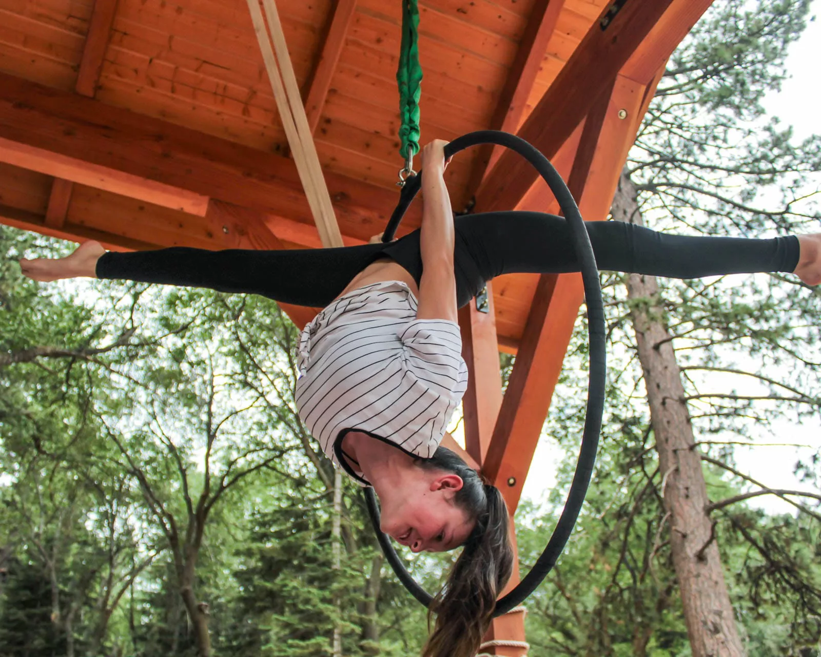 Girl on trapeze hoop upside down and doing a split