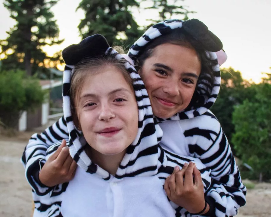 Two young girls wearing zebra onesies