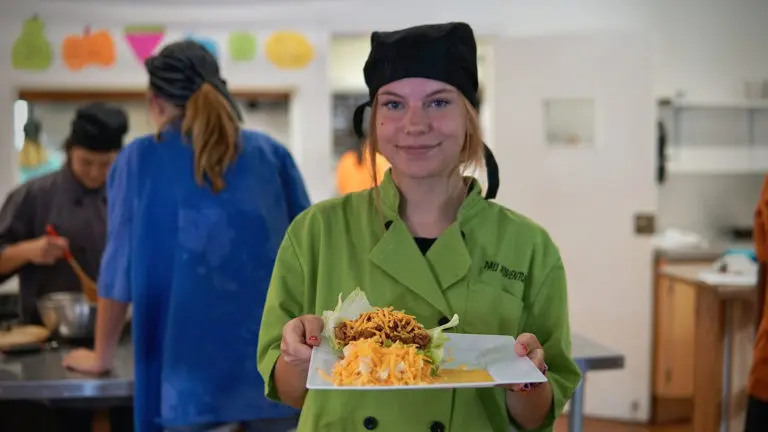 a girl holding a plate with salad on it