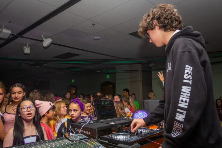 a kid in a dj booth while other kids dance