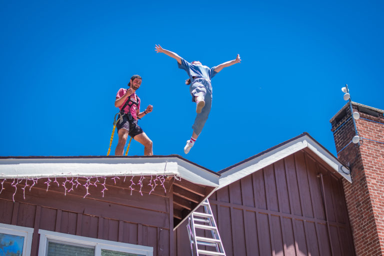 a girl performing a stunt jump off a roof