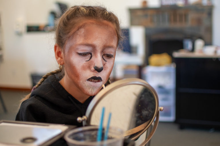 a girl painting her face to look like a cat