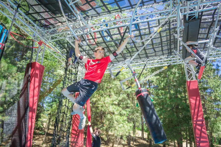 a boy swinging on an obstacle course