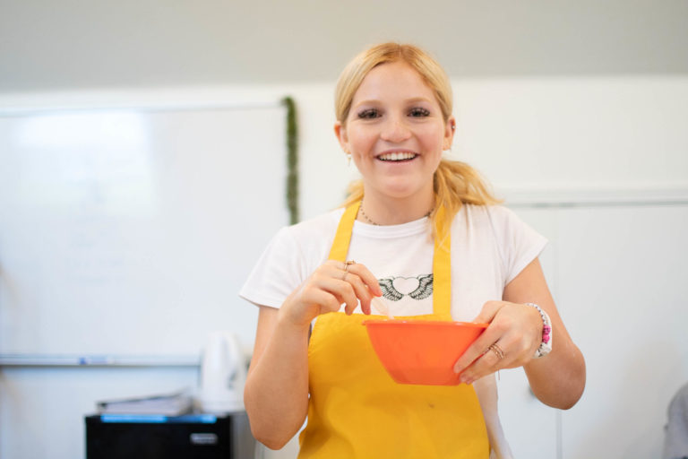 a girl smiling while mixing materials
