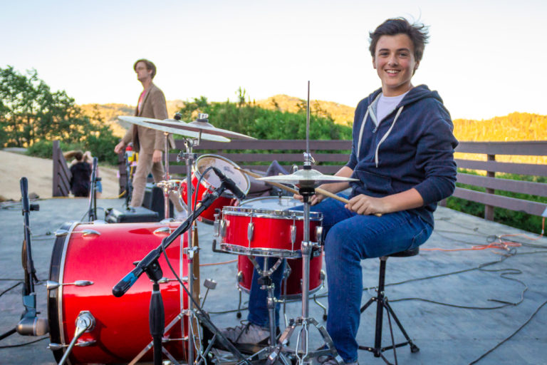 a boy playing a red drum set