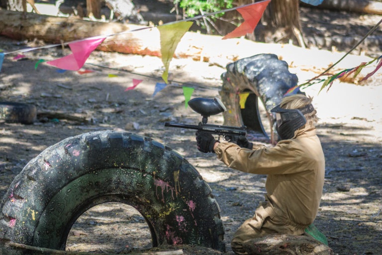 a girl taking cover while shooting a paint ball gun