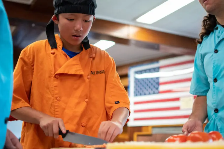 a boy cutting food with a knife