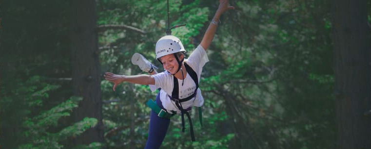 Camper riding the zipline through the forest