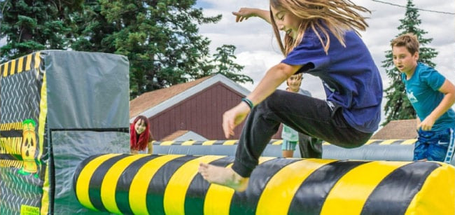 Camper leaping across an inflatable obstacle course