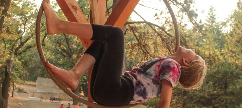 Camper hanging upside down on an aerial hoop